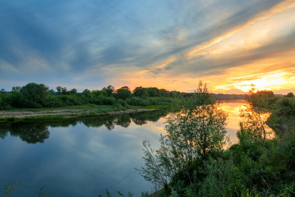 Sunset above the river at summer with cloudy sky background.