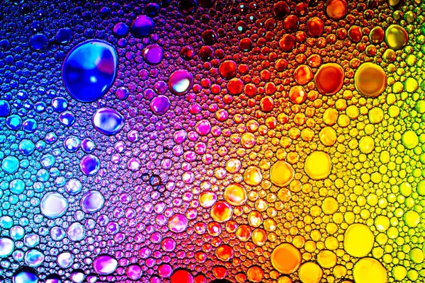 Colorful drops of oil on the water. Rainbow or spectrum colored — Stock Photo, Image