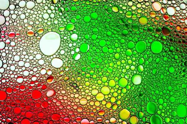 Coloridas gotas de aceite en el agua. Color amarillo, rojo y verde —  Fotos de Stock