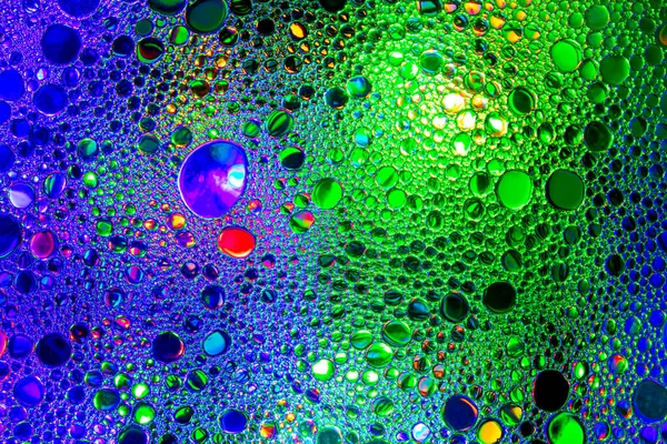 Colorful drops of oil on the water. Blue and green colored circl