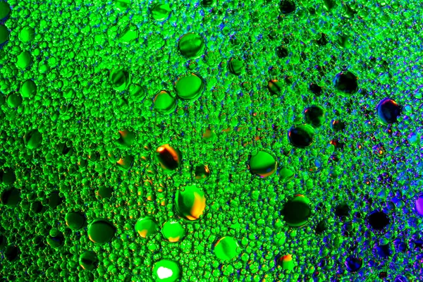 Colorful drops of oil on the water. Blue and green colored circl — Stock Photo, Image