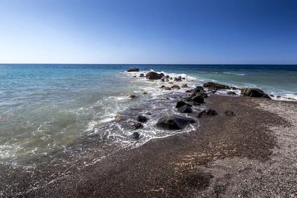 Surf de mer sur la plage avec sable volcanique noir et pierres . — Photo