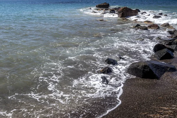 Surfe no mar na praia com areia vulcânica preta e pedras . — Fotografia de Stock