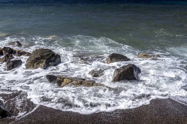 Surfe no mar na praia com areia vulcânica preta e pedras . — Fotografia de Stock