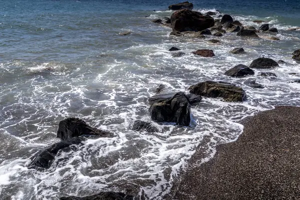 Surfe no mar na praia com areia vulcânica preta e pedras . — Fotografia de Stock