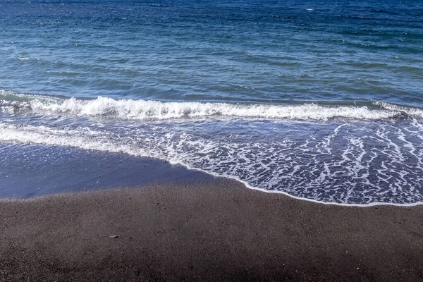 검은 개똥지빠귀 모래 가 해변에 밀려오는 파도. — 스톡 사진