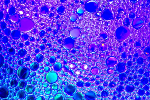 Colorful drops of oil on the water. Blue and violet colored circ — Stock Photo, Image
