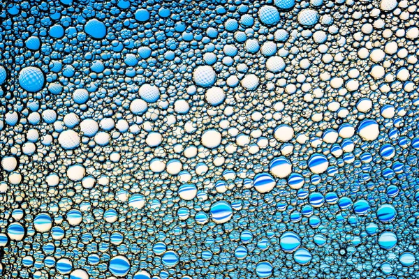 Vista superior em gotas coloridas de óleo na água. Círculos azuis — Fotografia de Stock