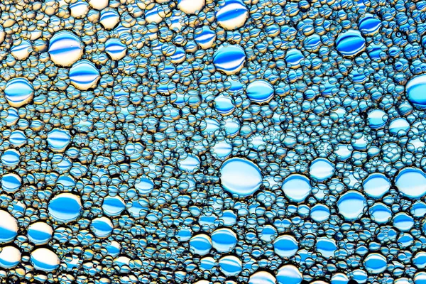 Κάτοψη σε πολύχρωμες σταγόνες λαδιού στο νερό. Μπλε και μωβ — Φωτογραφία Αρχείου