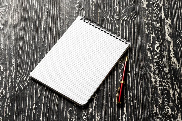 Het notitieboekje met vierkante pagina 's en pen op een zwarte tafel met een — Stockfoto