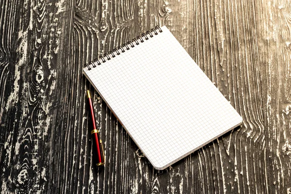 Het notitieboekje met vierkante pagina 's en pen op een zwarte tafel met een — Stockfoto