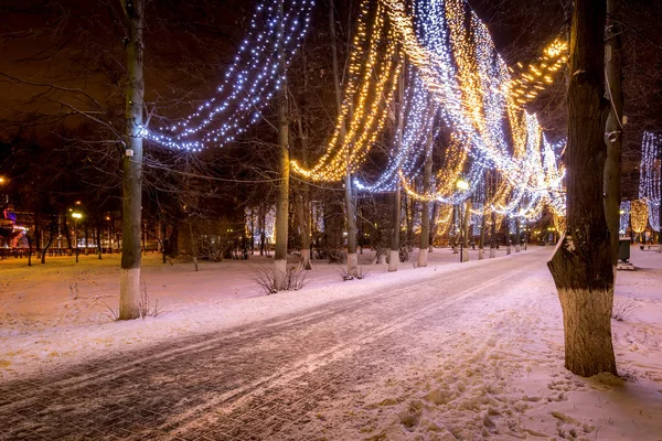 Parque de invierno por la noche con decoraciones navideñas, luces, bancos — Foto de Stock