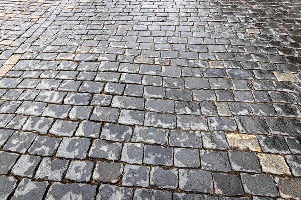 Top view on paving wet stone road after rain. Old pavement of gr — Stockfoto