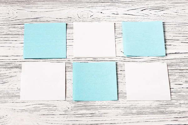 Bílé a modré papírové listy na dřevěném stole. Abstraktní pozadí — Stock fotografie