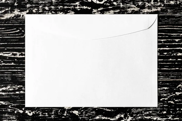 Sobre postal blanco sobre una mesa de madera negra. Fondo abstracto — Foto de Stock