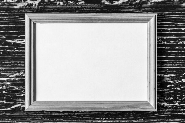 Photo frame on a black wooden table. Abstract background for design. Art stylized baner or mock up with copy space for a text. Monochrome.
