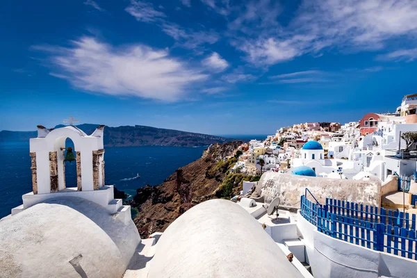 Oia city on Santorini island on a clear sunny day with church on a foreground. Cliff overlooking the sea and the caldera. — Stockfoto