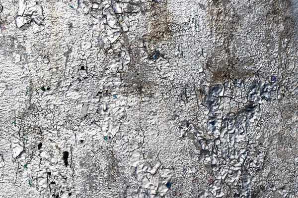 Fragment of silver graffiti painted on a wall. Bright abstract backdrop for design with peeling paint.