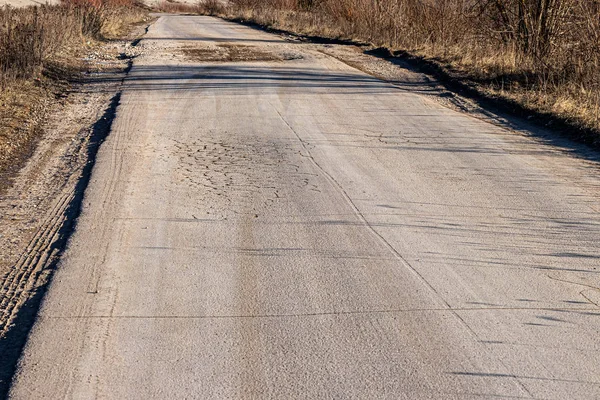 Trous et flaques d'eau sur l'asphalte des routes endommagées après la saison hivernale. Sale façon fissurée . — Photo