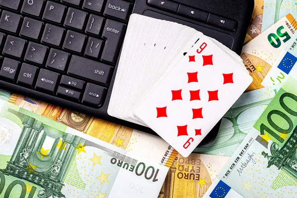 Euro bills, a deck of playing cards and a black keyboard. Concept of card games, casino or poker online. Online gambling.