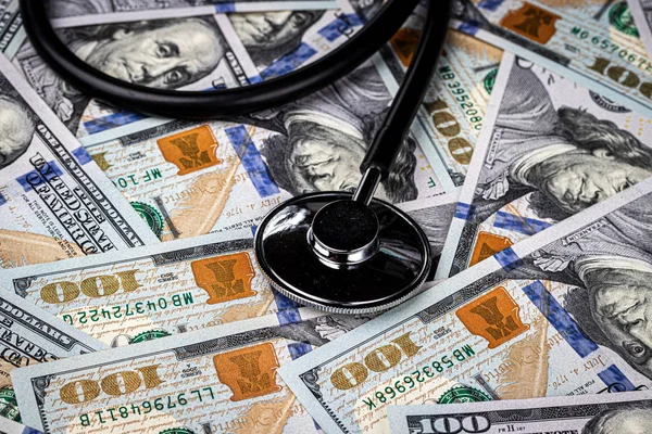 Stethoscope on the background of one hundred dollar bills. The concept of the expensive cost of healthcare or financing medicine.