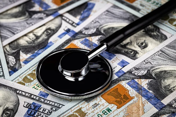 Stethoscope on the background of one hundred dollar bills. The concept of the expensive cost of healthcare or financing medicine.