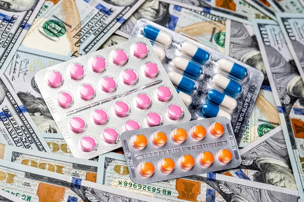 Plate with pills on the background of one hundred dollar bills. The concept of the expensive cost of healthcare or financing medicine.