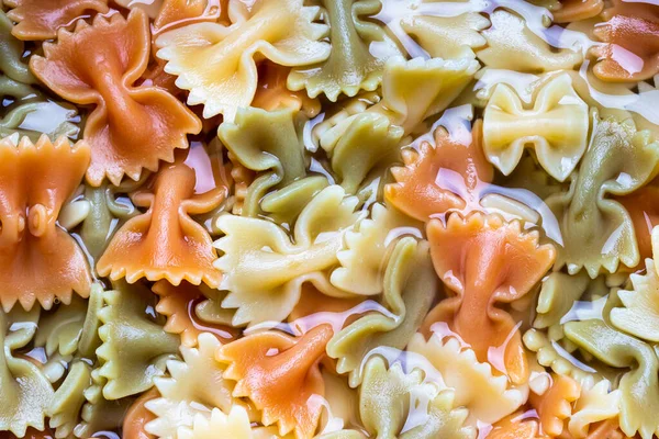 Colored italian cooked pasta farfalle tricolore abstract background. Traditional food. Texture.