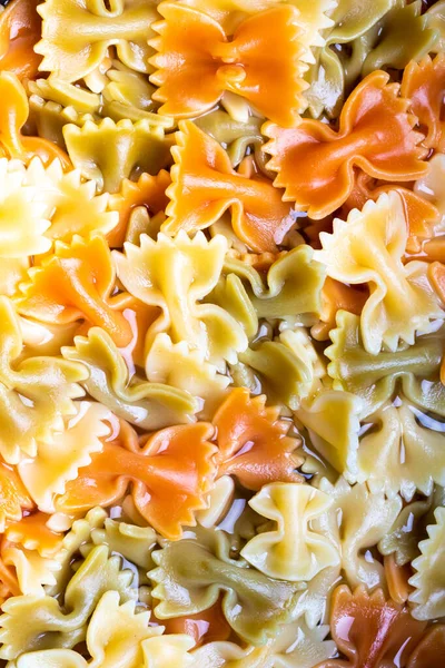 Colored italian cooked pasta farfalle tricolore abstract background. Traditional food. Texture.
