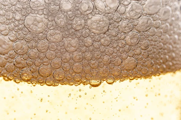 Texture of foam and bubbles in light beer. Abstract background for design.