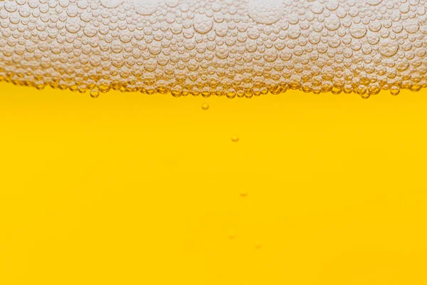 Texture of foam and bubbles in light beer. Abstract background for design.