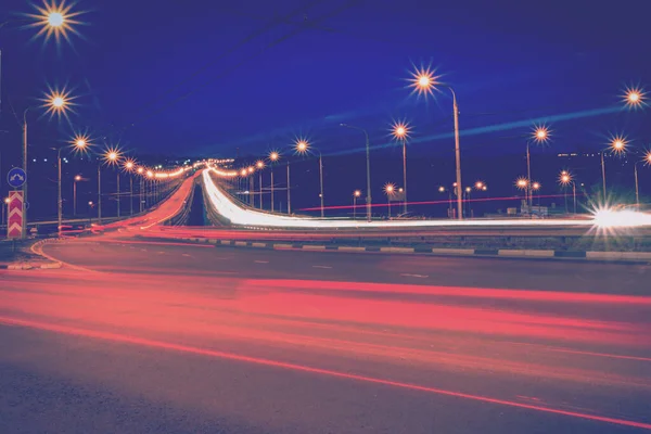 Moving car with blur light through city bridge at night.