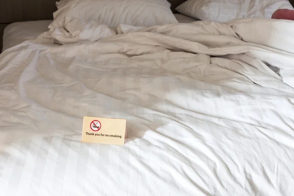 Dziękujemy za palenie znak na łóżku w pokoju hotelowym. — Zdjęcie stockowe