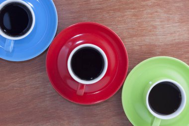 Ahşap masa arka plan üzerinde üç renkli bardak.