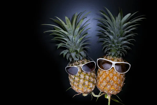 Ananas avec des lunettes de soleil sur fond noir . — Photo