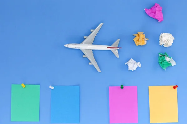 Airplane model with colorful blank paper note on blue background