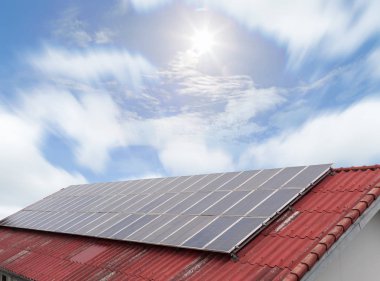 Güneş paneli ve kırmızı çatı mavi gökyüzü ve güneş güneş enerjisi paneli 