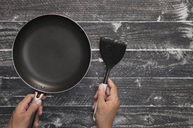 siyah ahşap bac üzerinde siyah spatula ile pişirme holding eller pan