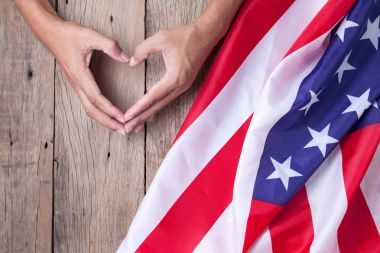 Amerikan bayrağı ile kalp sembolünü gösterirken eller tarafından yapılan jest