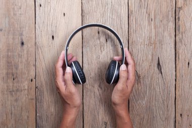 elini tut kulaklık ahşap tahta arka plan üzerinde.