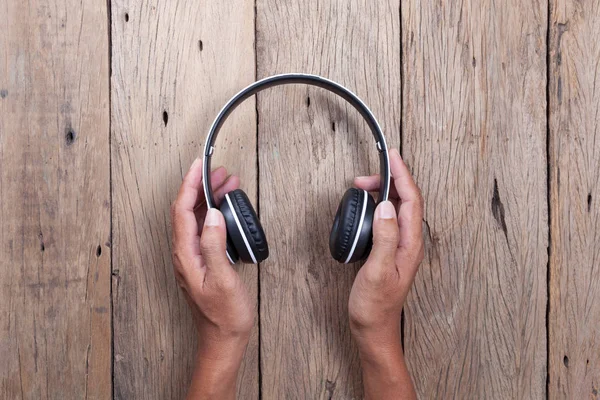 elini tut kulaklık ahşap tahta arka plan üzerinde.