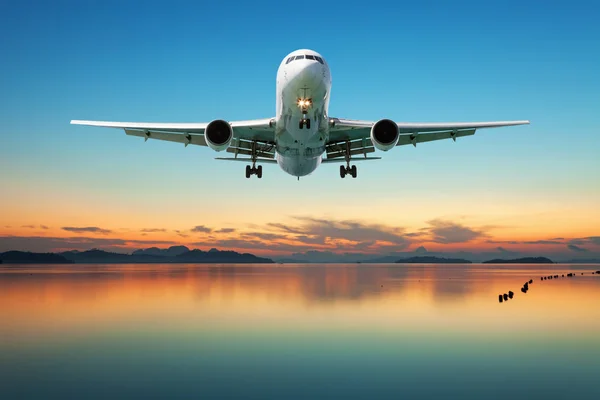 Airplane flying over tropical sea at beautiful sunset or sunrise — Stock Photo, Image