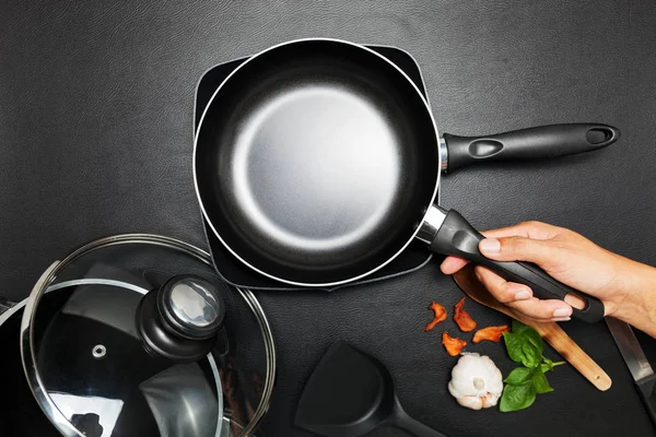 Siyah masada tava ve çömlek görünüyor..