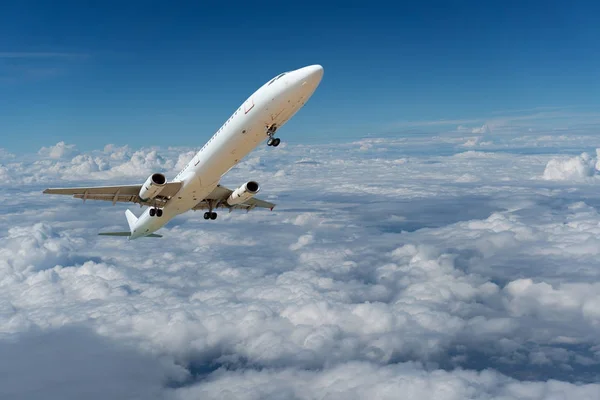 Avion commercial volant au-dessus des nuages et ciel bleu clair — Photo