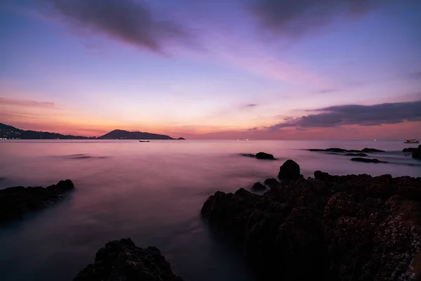 Lange blootstelling beeld van dramatische hemel zeegezicht met rock in de zonsondergang — Stockfoto