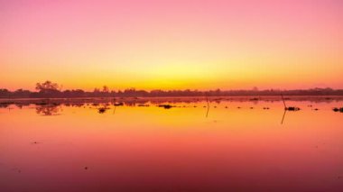 Güzel gündoğumunun ya da gölün üzerinde gün batımının manzarası suda yansıyan ışıkla.