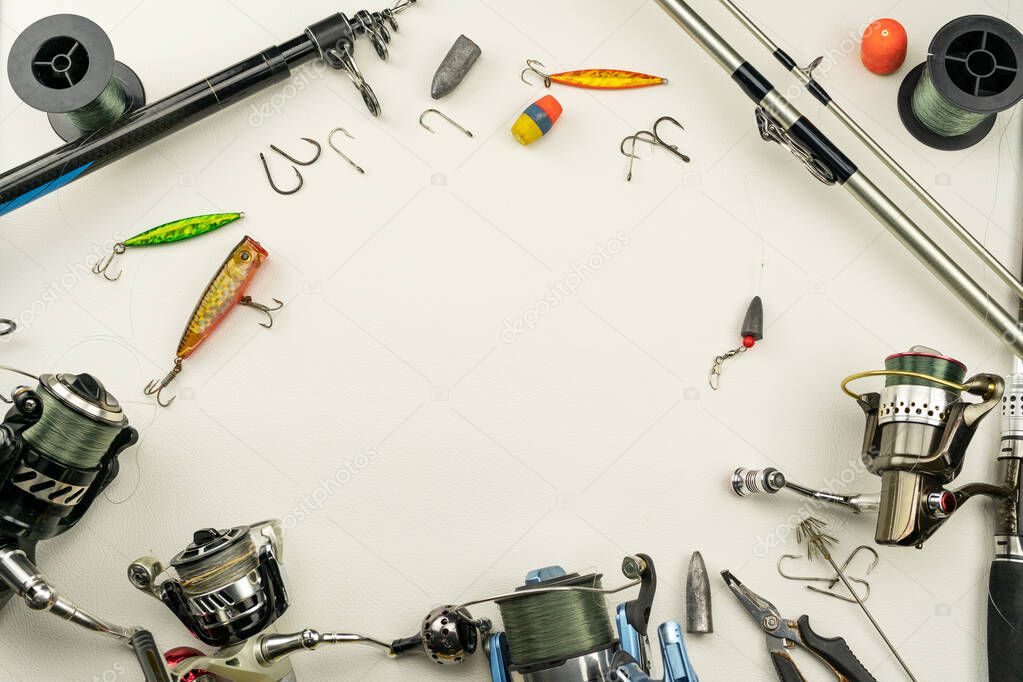 Fishing rods and reels fishing tackle on white leather background