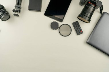 Beyaz deri arka planda profesyonel fotoğrafçının lensleri ve ekipmanlarıyla dijital kamera.