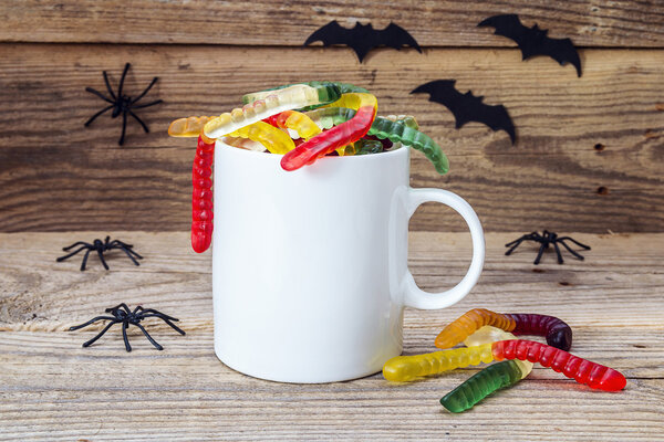 Halloween white coffee mug with gummi worms and spiders on the w