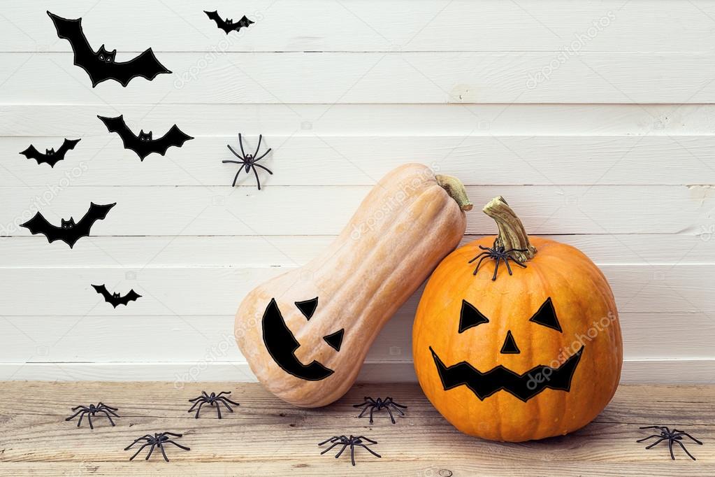 Two pumpkins with painted faces, decorative spiders and bats on 